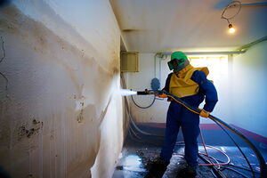 Mitarbeiter beim Sandstrahlen einer Betonwand